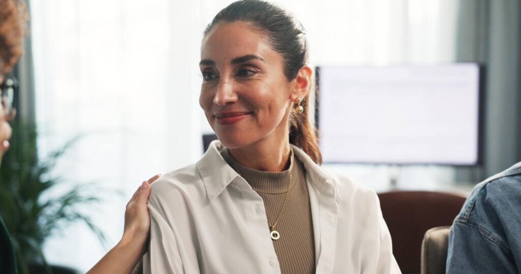 A picture of a smiling woman. A woman at her right has her hand on the smiling woman's shoulder. Alvarado Parkway Institute offers a supportive environment for schizophrenia treatment.